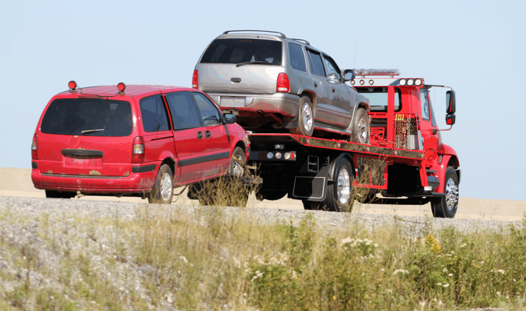Flatbed tow truck transporting a car on a New Jersey highway during daylight for professional vehicle recovery.