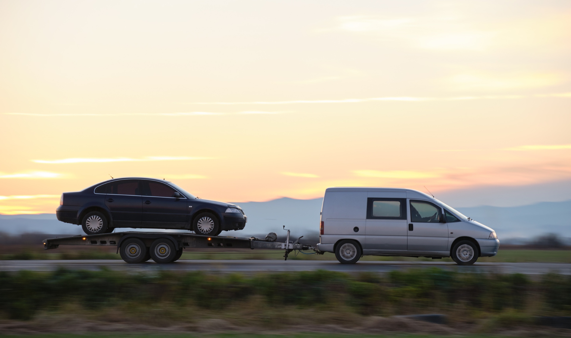Flatbed tow truck approaching with flashing lights for a quick 15-minute roadside response in Central NJ.