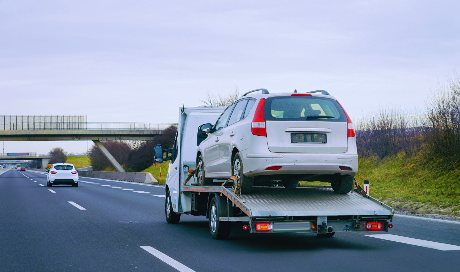 A professional tow truck driver assisting a stranded driver on a highway shoulder at night.