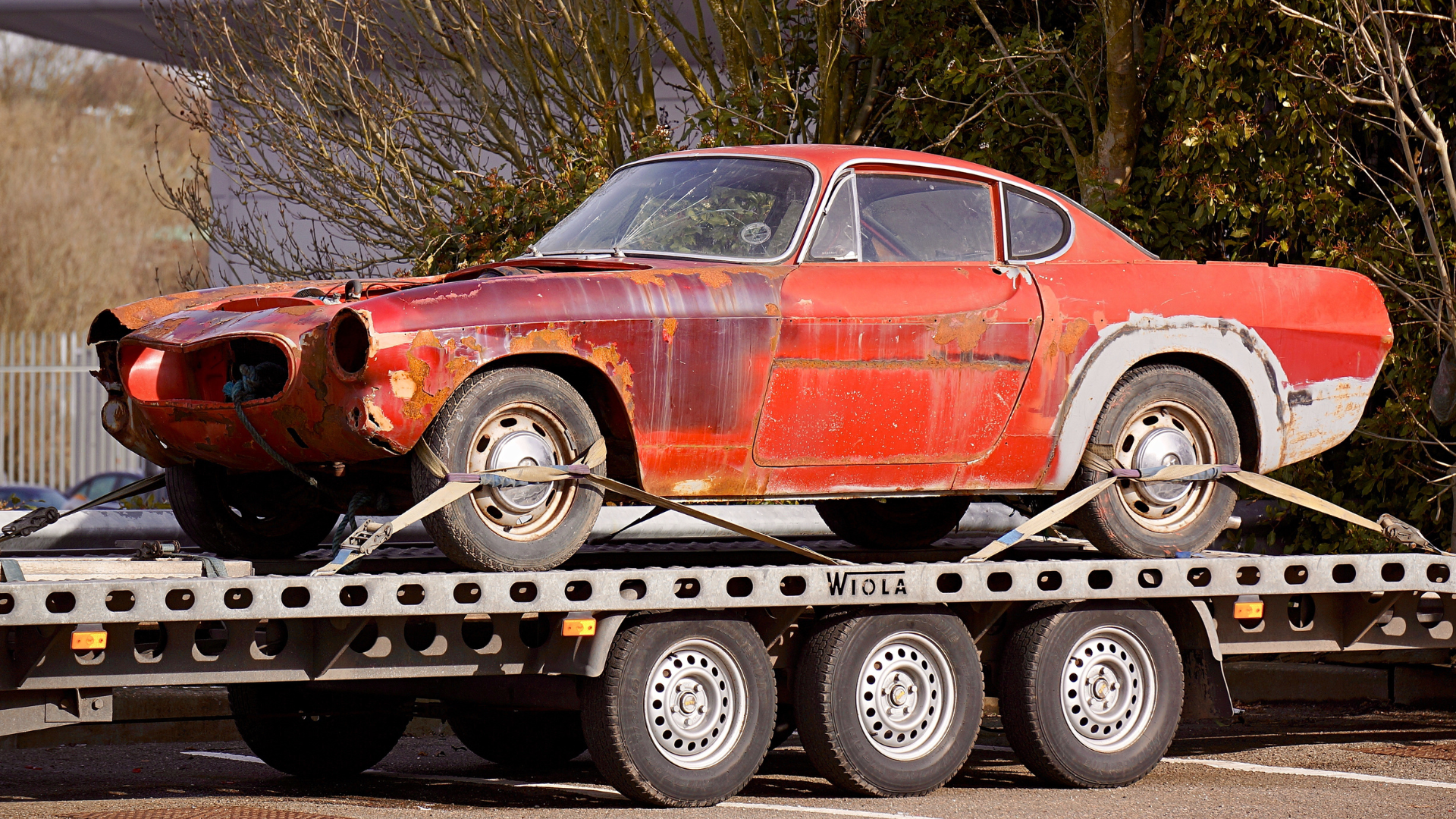 Rusty red vintage car secured on a New Jersey Towing bed.